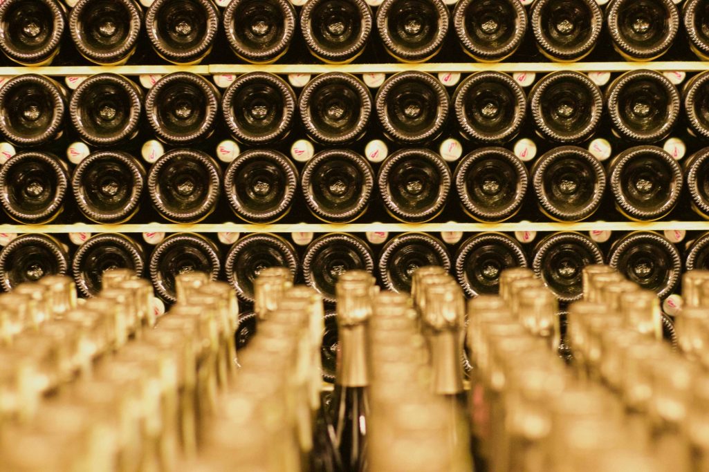 In Regalen gelagerte Weinflaschen in einem Weinkeller, im Vordergrund unscharfe Flaschenhälse.