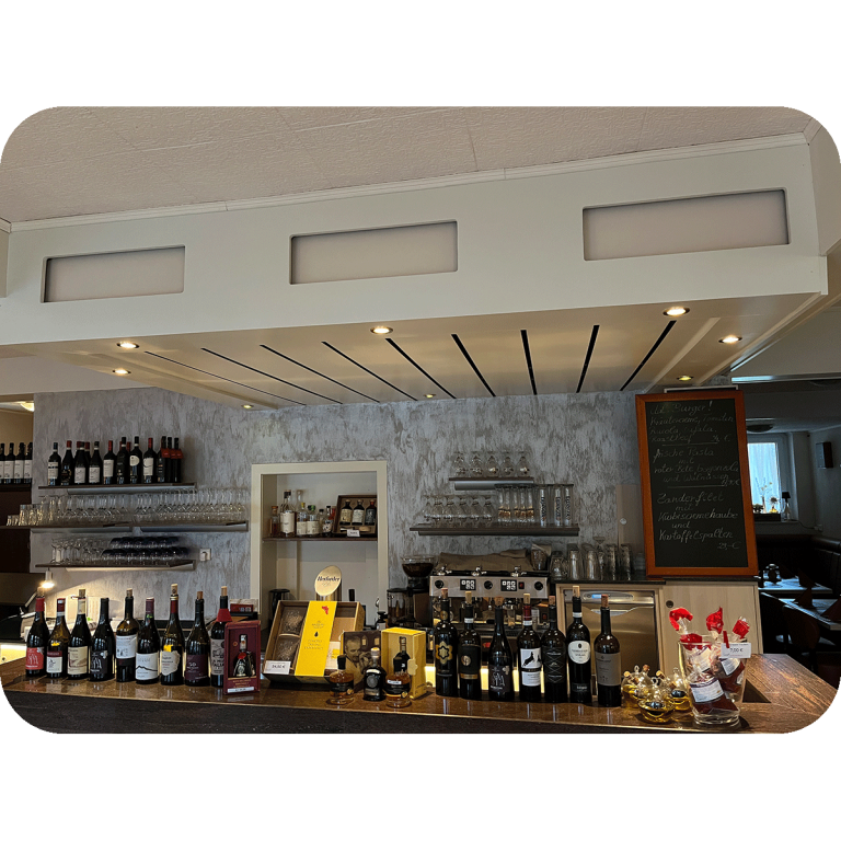 Ristorante Apollo in Blomberg. Moderne Bar mit Regalen, Weinen, Spirituosen und einer Tafel im Hintergrund.